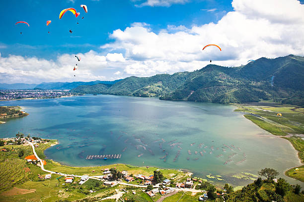 Paragliders flying above the lake and cultural landscape of Pokhara